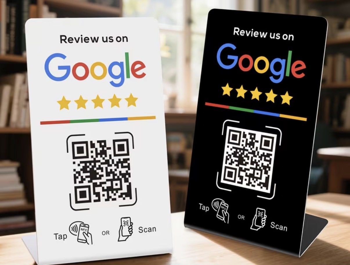 Two Google review stands, one white and one black, on a wooden counter. Each shows Review us on Google, five stars, a QR code and Tap or Scan icons